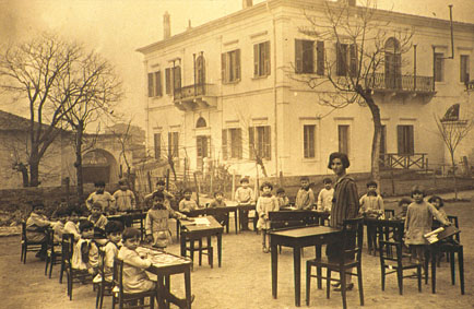 1930, η Α' τάξη του Προτύπου με φόντο το Διδασκαλείο. Δασκάλα η Αλεξάνδρα Κεσσανλή.